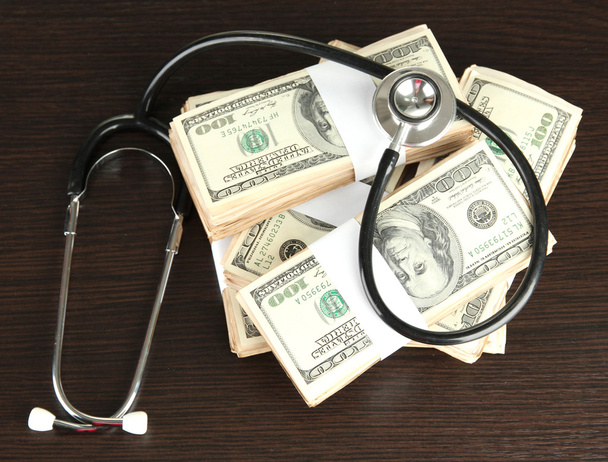 Healthcare cost concept: stethoscope and dollars on wooden background - Foto, Bild