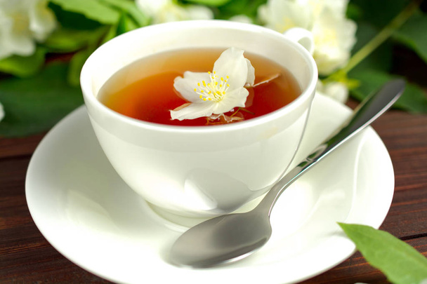 Čaj s jasmínem v bílém cup na dřevěný stůl. - Fotografie, Obrázek
