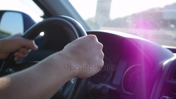 O tipo conduz um carro num dia de sol. A hora do pôr-do-sol. Mãos e volante close-up
 - Filmagem, Vídeo