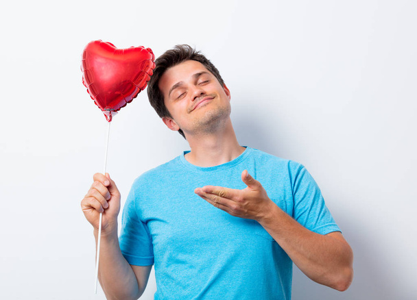 homem em azul t-shirt com forma de coração balão brinquedo
 - Foto, Imagem
