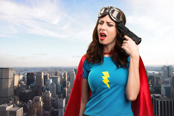 Hübsches Superheldenmädchen beim Selbstmord mit der Stadt im Hintergrund - Foto, Bild