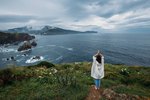 girl in poncho standing on cliff - Foto, afbeelding