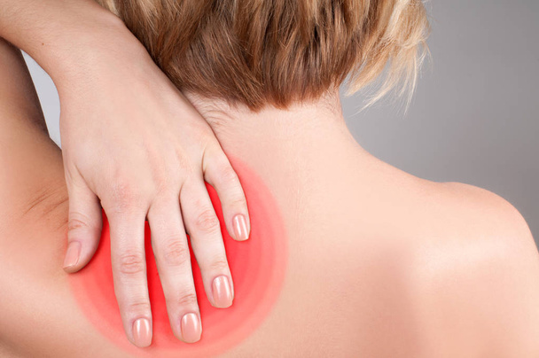 Young woman with shoulder pain, massaging her shoulder - Fotografie, Obrázek