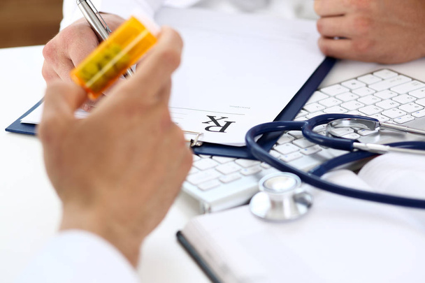 Médico de medicina masculina escrever prescrição na mesa de trabalho
 - Foto, Imagem