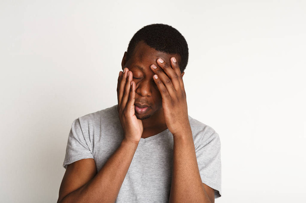 Erschöpfter schwarzer Mann hält Hände auf dem Kopf, negative Emotionen - Foto, Bild
