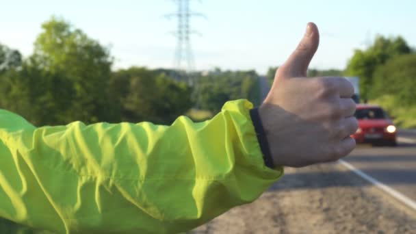 Stoppolás utazás fiatal felnőtt férfi hüvelykujját felfelé mutató, államközi autópályán - Felvétel, videó