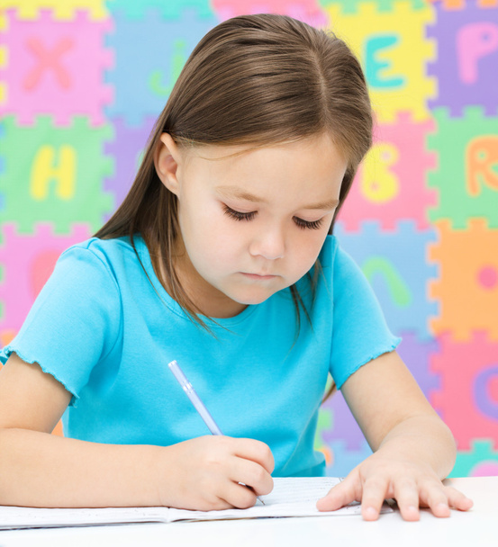 Little girl is writing using a pen - 写真・画像