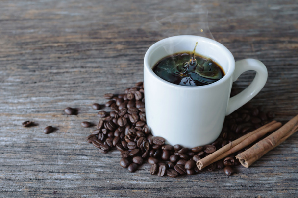Ζεστό καφέ σε λευκό κούπα με splash και κόκκους καφέ στο ξύλο bac - Φωτογραφία, εικόνα