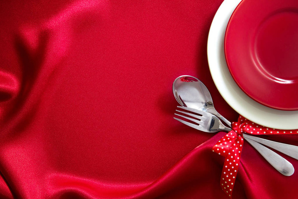 la plaque vide rouge avec fourchette et cuillère sur un tissu de soie rouge pour d
 - Photo, image