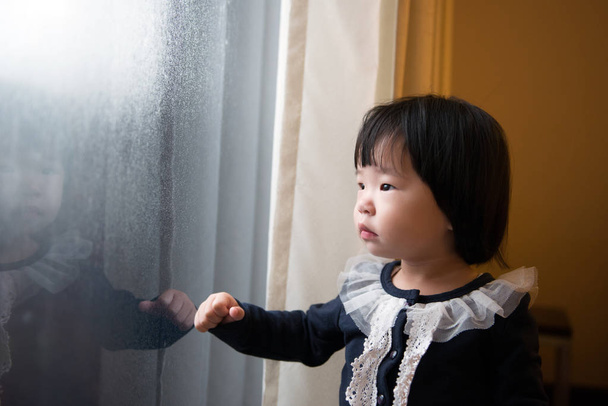 asiatisches Kleinkind beobachtet den Schnee - Foto, Bild
