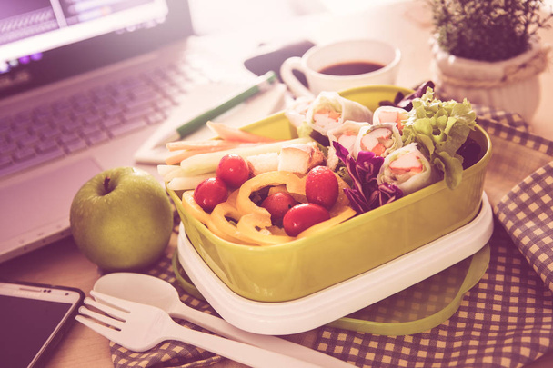 Fechar a caixa de almoço verde no local de trabalho da mesa de trabalho, Cura
 - Foto, Imagem