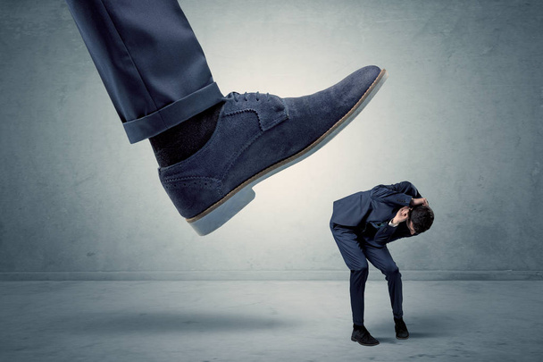 Employee getting trampled by big shoe - Foto, Bild