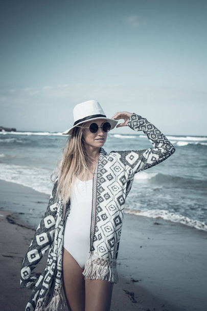 Giovane donna sexy con cappello bianco che cammina sulla spiaggia di sabbia bianca un'isola tropicale di Bali nella giornata di sole. Costo dell'oceano
. - Foto, immagini