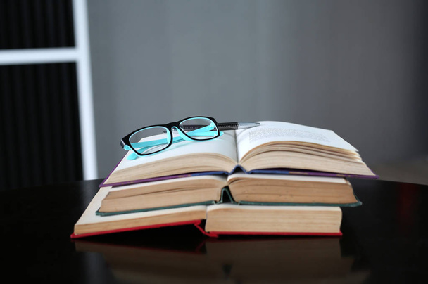 Open book, hardcover books and glasses on wooden table. Education background. - Фото, изображение