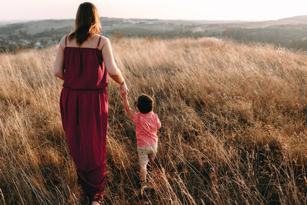 madre cammina con figlio in erba alta
 - Foto, immagini