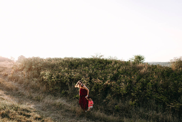Äiti kävelee poikansa kanssa korkealla ruoholla
 - Valokuva, kuva