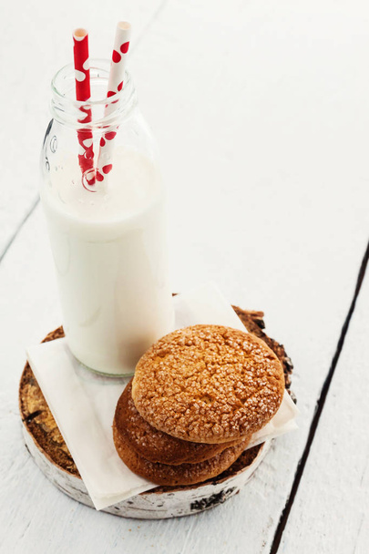 Una pila de galletas redondas de pan corto y una botella de leche, en una w
 - Foto, Imagen