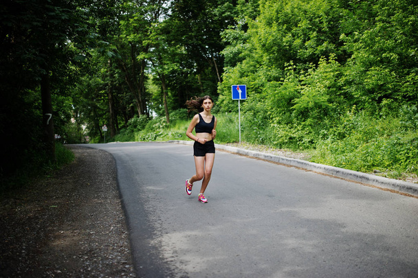 Sport girl at sportswear running in a green park and training at - Фото, зображення