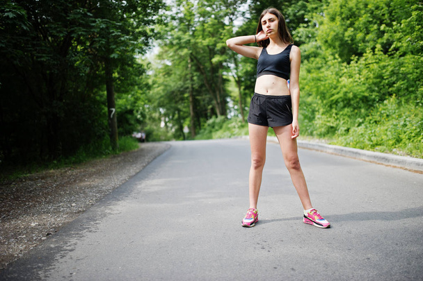 Sport girl at sportswear exercising in a green park and training - 写真・画像