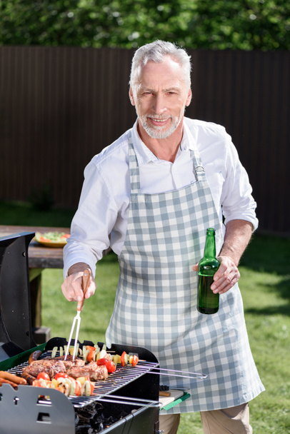 uomo dai capelli grigi preparare barbecue
 - Foto, immagini