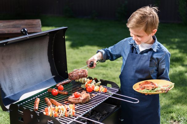 kid boy preparing stakes on grill - Φωτογραφία, εικόνα