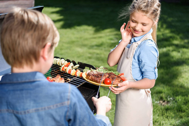 kids preparing meat and vegetables on grill - Photo, Image