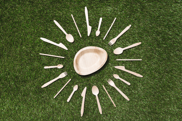 wooden cutlery items and plate on grass - Fotó, kép