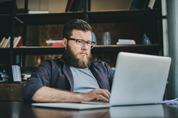 bearded man working on laptop at home - Photo, Image