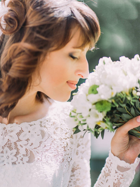 The close-up side portrait of the bride smelling the wedding bouquet. - Foto, Imagem