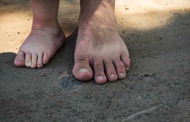 the feet of a little boy and a man on the sand - Foto, Bild