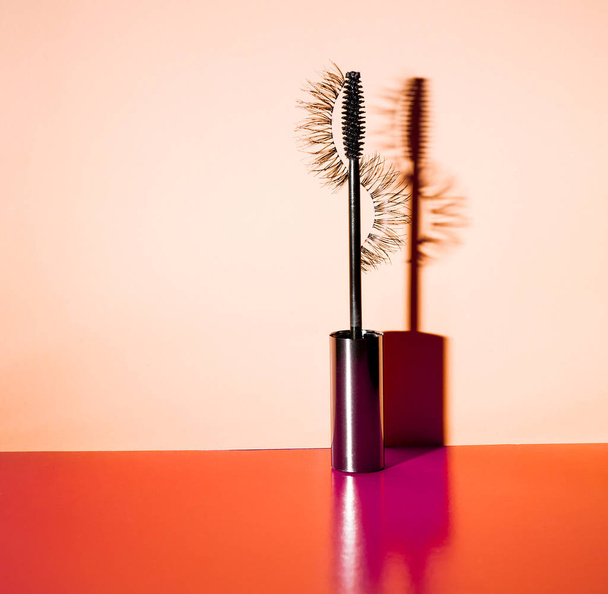 Applicator mascara and false eyelashes with drop shadow on orange background - Photo, Image