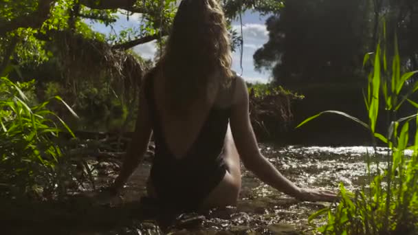 Bir nehir sığ suda oturan genç kadın - Video, Çekim