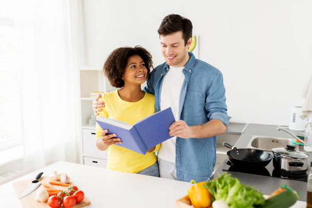 happy couple with cooking book at home kitchen - Foto, Imagen
