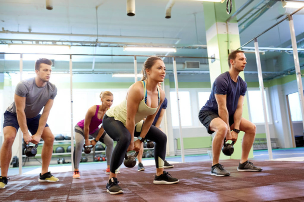 group of people with kettlebells exercising in gym - Photo, Image