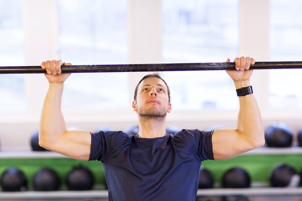 man exercising on bar and doing pull-ups in gym - 写真・画像