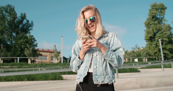 Young blonde woman using phone in a city. - Photo, Image