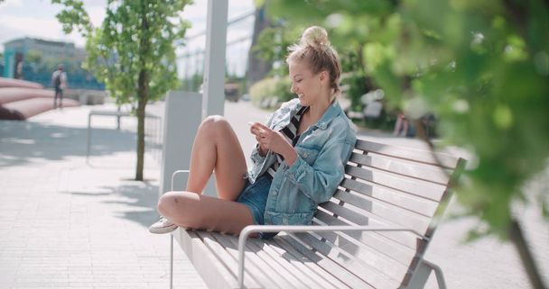 Young blonde woman using phone in a city. - Foto, imagen