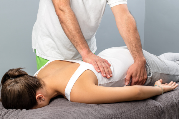 Fizjoterapeuta robi masaż na kobiece dolnej części pleców. - Zdjęcie, obraz