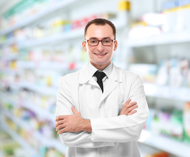Male pharmacist at work. Blurred shelves with pharmaceutical products on background - Φωτογραφία, εικόνα