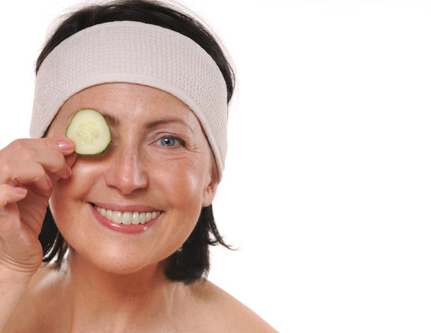 Mulher madura alegre segurando pedaço de pepino na frente de seu olho
 - Foto, Imagem