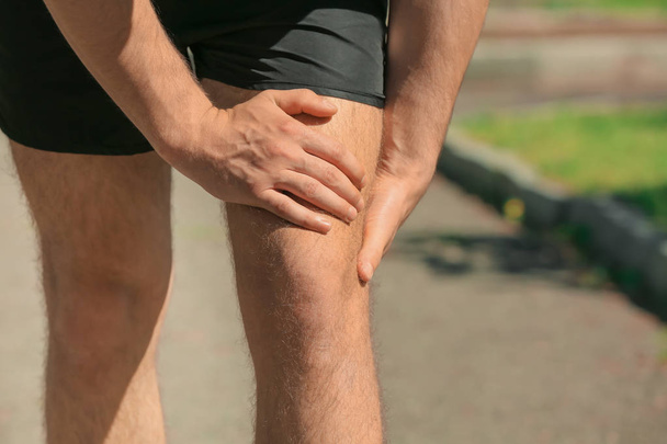 man suffering from pain in leg - Foto, Bild