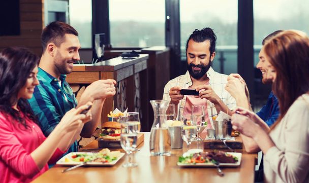 happy friends taking picture of food at restaurant - 写真・画像
