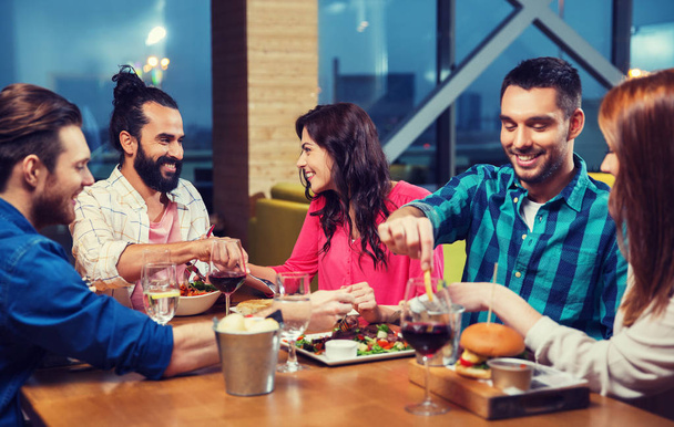 friends eating and tasting food at restaurant - Фото, зображення