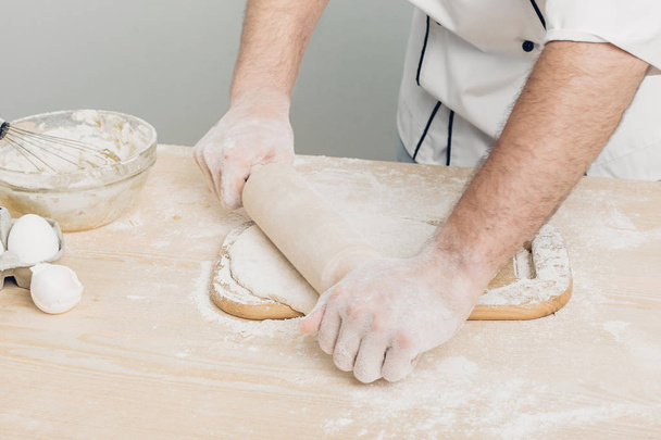 Man Chef  baking dough with rolling pin in kitchen - Fotó, kép