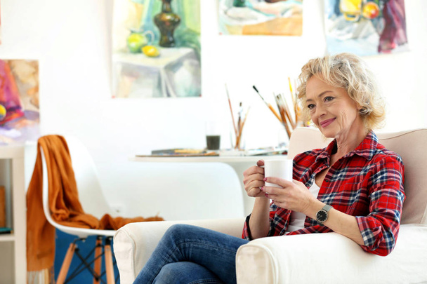 Artista femenina mayor bebiendo café en estudio
 - Foto, imagen
