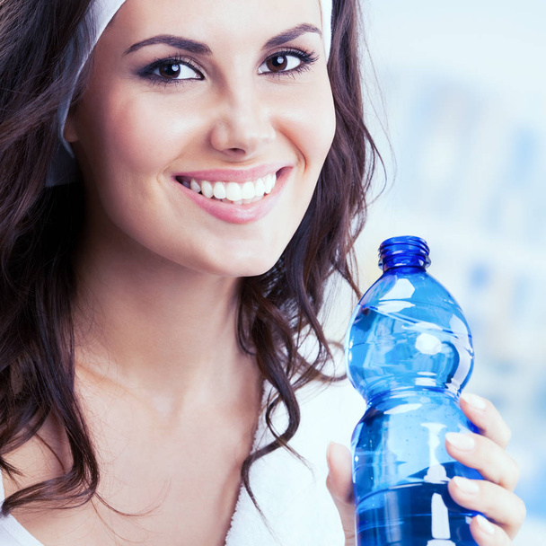 Portrait of smiling young woman with bottle of water - 写真・画像