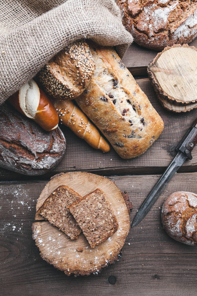Delicious fresh bread inside a sack on wooden background - Foto, imagen