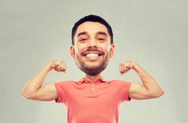 smiling man showing biceps over gray background - Foto, afbeelding
