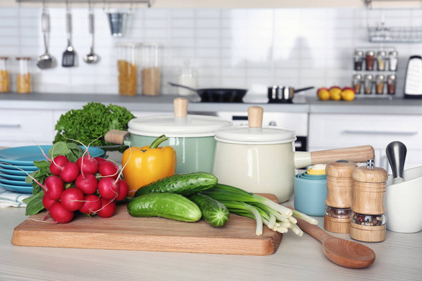 Свіжі овочі та посуд для уроків приготування їжі на дерев'яному столі
 - Фото, зображення