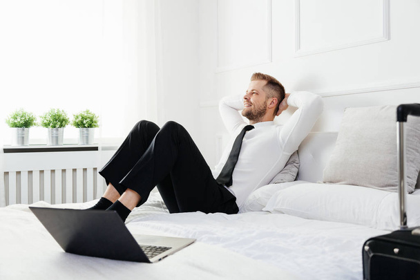 Бізнесмен розслабляється на ліжку у своїй кімнаті готелю
 - Фото, зображення